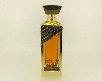 May include: A gold bottle of perfume with a gold cap and a label that reads "Jardins de Bagatelle Guerlain Paris".
