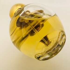 May include: A clear glass bottle with a gold cap filled with a yellow liquid. The bottle has a textured surface and the text "MARVEL" is printed on the bottom.