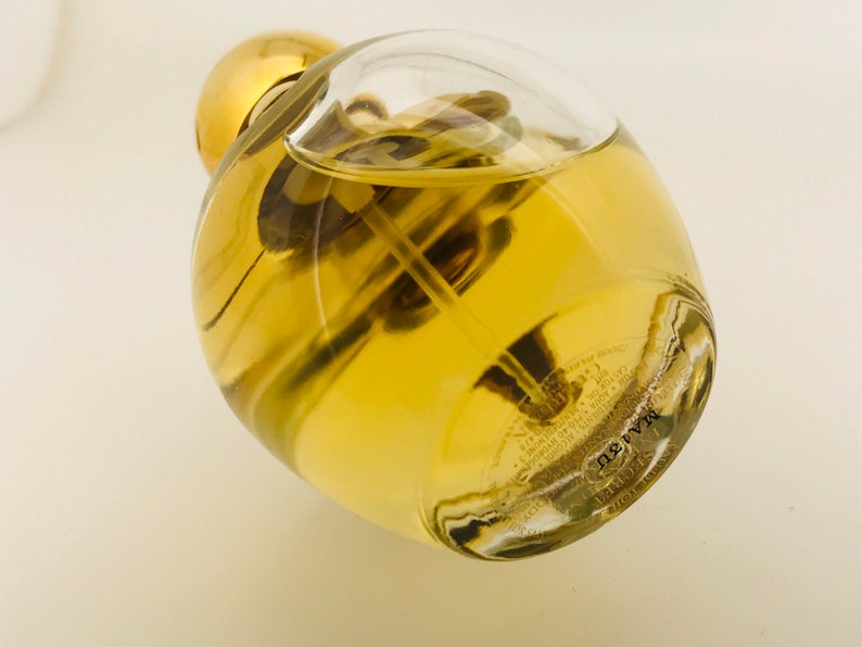 May include: A clear glass bottle with a gold cap filled with a yellow liquid. The bottle has a textured surface and the text "MARVEL" is printed on the bottom.