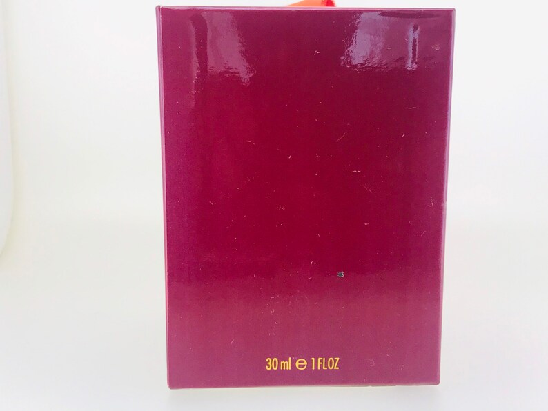 May include: A burgundy box with gold lettering that reads "30 ml e 1 FLOZ".