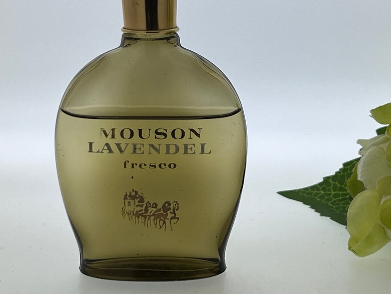 Op de afbeelding: Een bruine glazen fles Mousson LavendeL fresco cologne. De fles heeft een gouden dop en een gouden etiket met de productnaam en het woord "fresco".