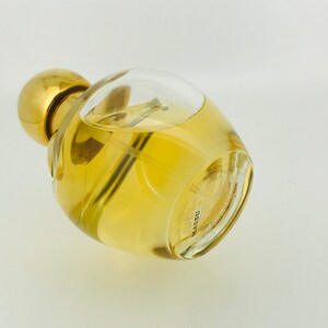 May include: A clear glass bottle with a gold cap and a yellow liquid inside. The bottle is lying on its side and the bottom of the bottle is visible. The bottom of the bottle has the word "DELVYN" printed on it.