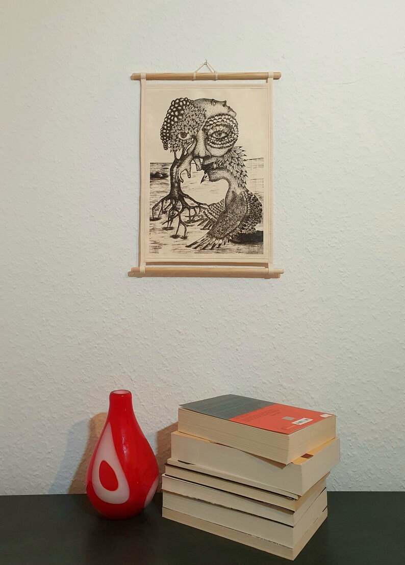 May include: A black and white print of a surreal creature with a human face and a bird-like body. The print is framed and hanging on a white wall.