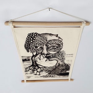 May include: Black and white illustration of a surreal creature with a tree growing out of its head. The creature has a large eye and is surrounded by leaves and branches. The illustration is printed on a white canvas and framed with a wooden frame.