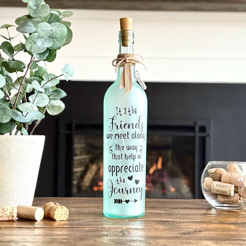 Clear recycled winefrosted with spray paint. Black vinyl words It's the friends we meet along the way that help us appreciate the Journey. Includes batteryoperated fairy lights attached to plastic cork with on/off switch. Topped off with twine and your choice of ribbons.
