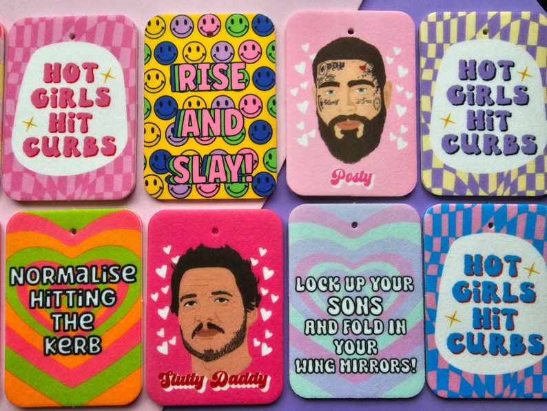 May include: Ten colorful car air fresheners with various designs and text. The designs include smiley faces, hearts, and checkered patterns. The text includes "Hot Girls Hit Curbs", "Rise and Slay", "Lock Up Your Sons and Fold In Your Wing Mirrors", "Normalize Hitting the Kerb", and "Slutty Daddy".