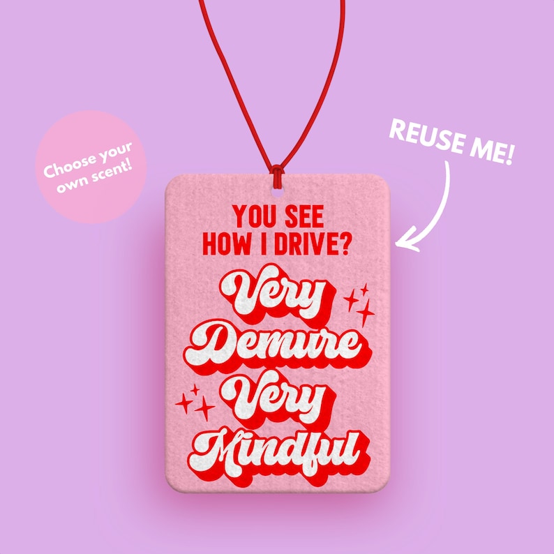 Peut inclure: Diffuseur de parfum de voiture rose avec le texte "YOU SEE HOW I DRIVE? Very Demure Very Mindful" en rouge et blanc dans une police r&eacute;tro. Le diffuseur est suspendu &agrave; une ficelle rouge.