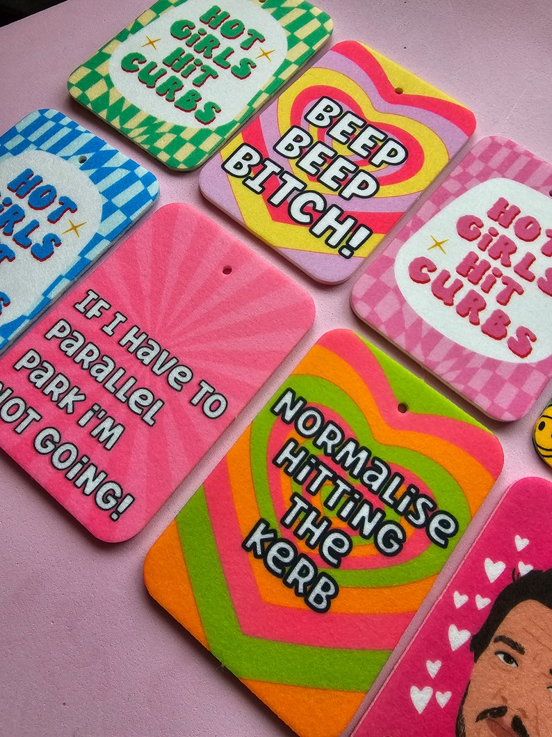 May include: A set of colorful car air fresheners with humorous phrases like "Hot Girls Hit Curbs", "Beep Beep Bitch!" and "Normalise Hitting the Kerb".