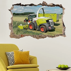 May include: A green and gray Claas Jaguar 970 forage harvester with a green trailer in a field of green grass. The harvester has a large, round, red tire on the right side.