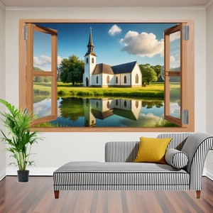 May include: A white church with a tall steeple reflected in a pond, seen through an open window. The scene is framed by a wooden window frame and set against a backdrop of a light blue sky with fluffy white clouds.