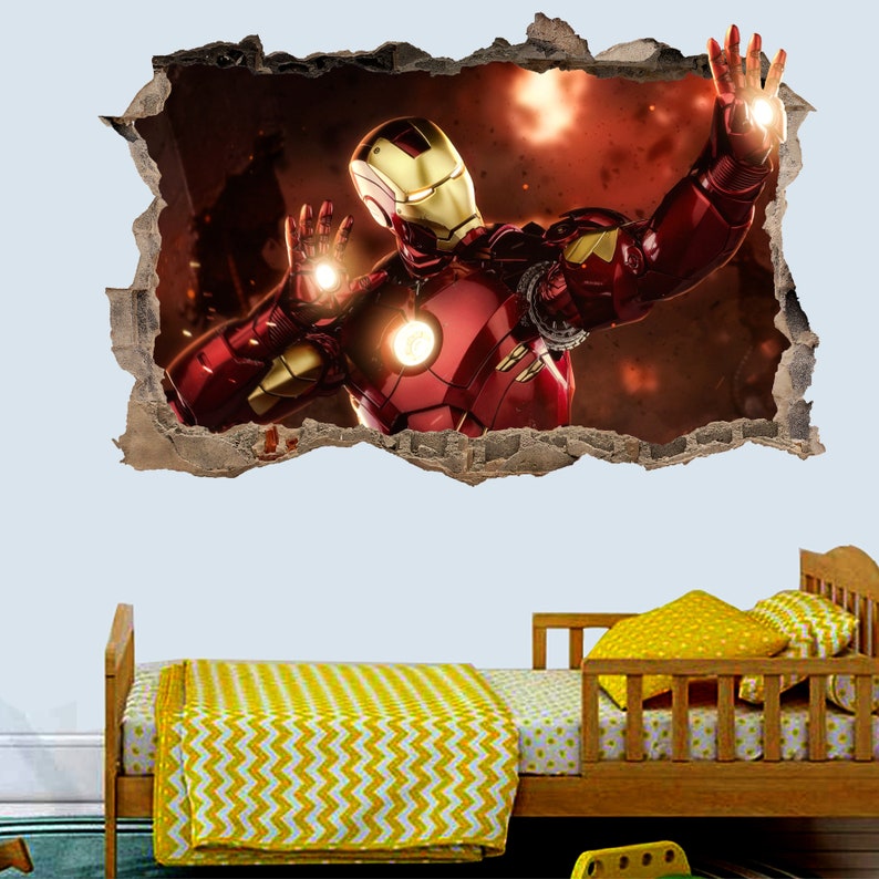 May include: A red and gold Iron Man superhero character wall decal with a 3D effect. The decal is placed on a wall above a wooden bed with yellow and white bedding.