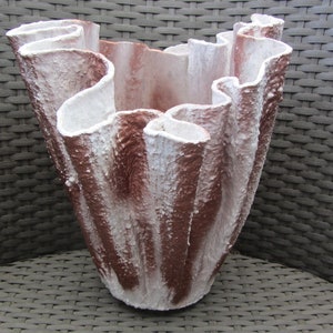 Peut inclure: Un pot en céramique blanc et brun avec un design unique, ondulé et organique. Le pot est fait d'un matériau texturé et a une large ouverture en haut.