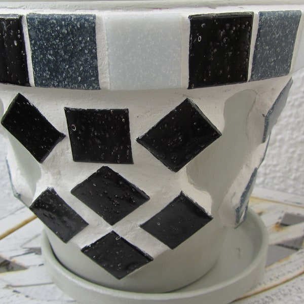 Pot de fleur gris avec des pierres blanches, grises et noires de mosaïque de verre.