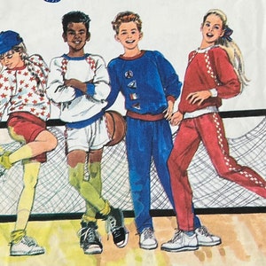 May include: Four people wearing different colored sweatshirts and pants. The people are standing in front of a net. One person is holding a basketball.