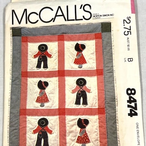 May include: A McCall's 8474 sewing pattern envelope featuring a quilt design with six appliqued figures in red, black, and white. The quilt has a red and white checkered border and a dark blue and white checkered outer frame with text.