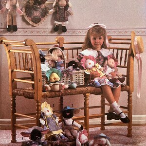 May include: A wooden bench with a wicker seat, a little girl is sitting on the bench holding two stuffed animals. There are several other stuffed animals on the bench and on the floor. The stuffed animals are all dressed in different outfits and have different features. The bench is in a room with a floral wallpaper and a floral patterned rug.