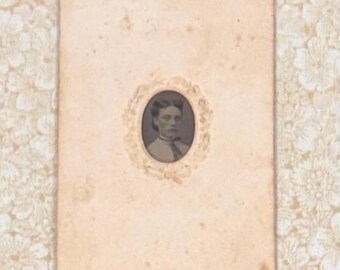 May include: Antique oval portrait photograph of a woman in a decorative frame. The sepia-toned image is set against a cream-colored background with a floral pattern. The portrait is a vintage piece, likely from the late 19th or early 20th century.