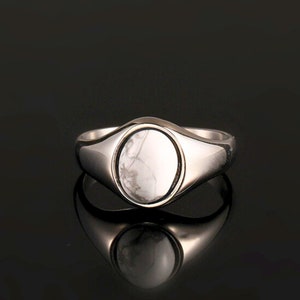 Peut inclure: Une bague signet en argent avec une pierre ovale blanche sertie au centre.