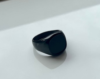 May include: A black signet ring with a smooth, oval-shaped top.