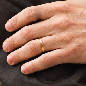 Peut inclure: Une simple bague en or portée à un doigt.