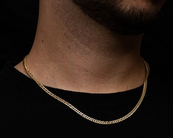 Könnte beinhalten: Eine goldene Kettenkette, die um den Hals einer Person getragen wird. Die Kette ist im Curb-Stil mit glänzender Oberfläche.