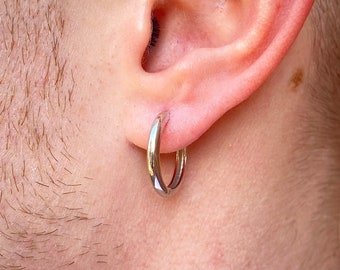 May include: A silver hoop earring is worn in the ear. The earring is a simple, polished design. The image is a close-up of the ear and the earring, with the person's neck and shoulder visible in the background.