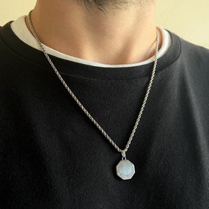 以下が含まれることがあります： 銀色のロープチェーンネックレスに、銀色の八角形のペンダントがついたもの