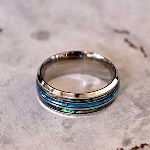May include: A silver ring with three blue and green abalone shell inlays.