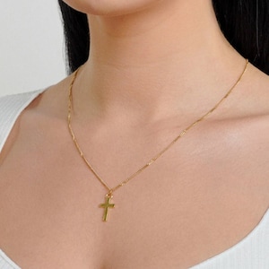May include: A gold chain necklace with a small gold cross pendant.