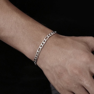 May include: A silver curb chain bracelet with a classic design. The bracelet is made of metal and has a polished finish.