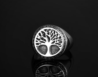 May include: A silver ring with a tree of life design. The ring is round and has a textured surface.