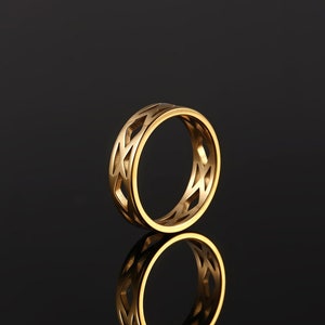 May include: A gold-colored ring with a geometric design. The ring is made of metal and has a smooth finish.
