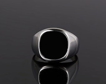 May include: A silver signet ring with a black oval stone.