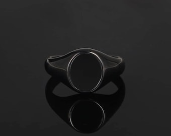 May include: A black onyx signet ring with a smooth, oval-shaped stone set in a silver band.