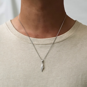 May include: A silver chain necklace with a small silver wing pendant.