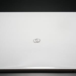 Puede incluir: Dos peque&ntilde;os pendientes de aro plateados. Los pendientes son circulares y entrelazados, con un acabado met&aacute;lico brillante. Se encuentran sobre un fondo blanco liso.