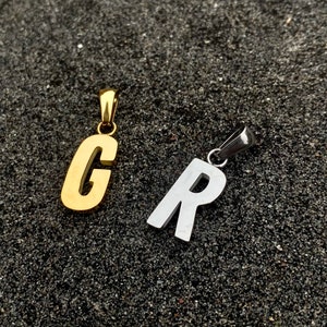 May include: Two metal letter pendants, one gold and one silver. The gold pendant is the letter "C" and the silver pendant is the letter "R".