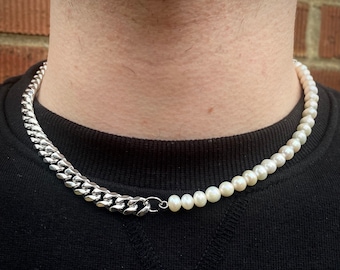 May include: A silver chain necklace with a pearl strand attached to one end. The necklace is worn by a person.