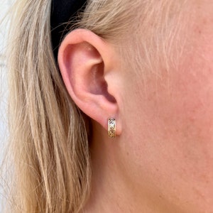 May include: Gold hoop earrings with a delicate floral design.