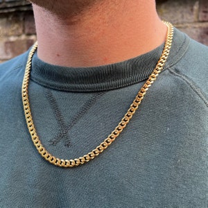 May include: A gold chain necklace with a curb link style. The chain is thick and has a shiny finish.