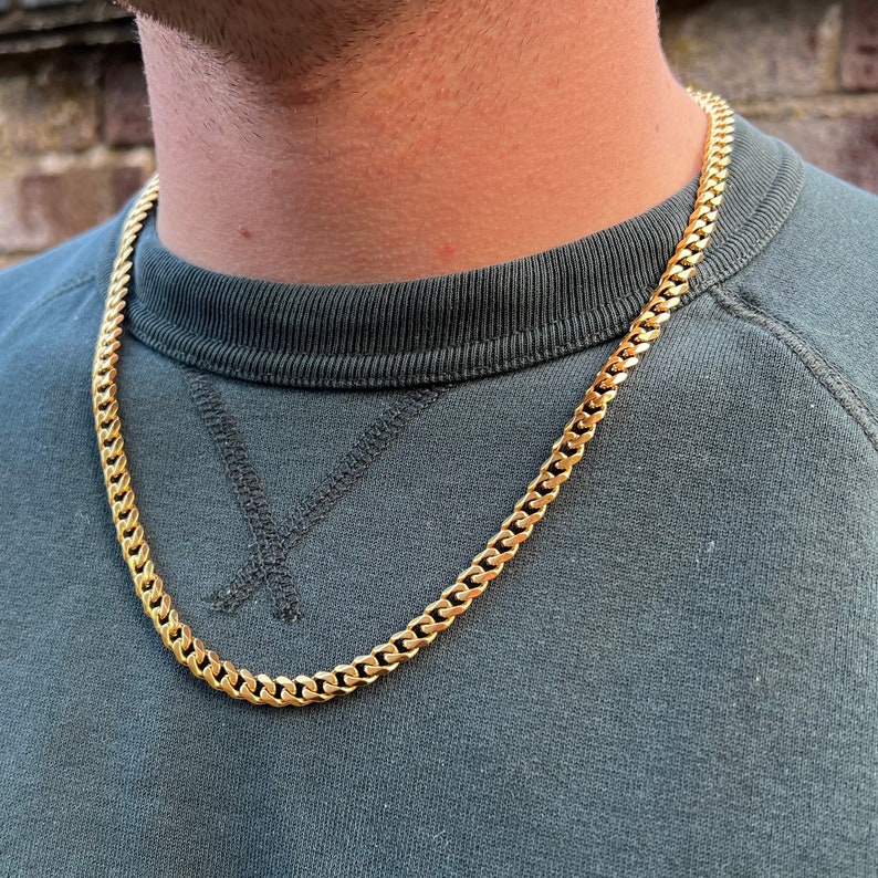 May include: A gold chain necklace with a curb link style. The chain is thick and has a shiny finish.