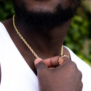 Puede incluir: Un collar de cadena de cuerda dorada usado por una persona con barba.