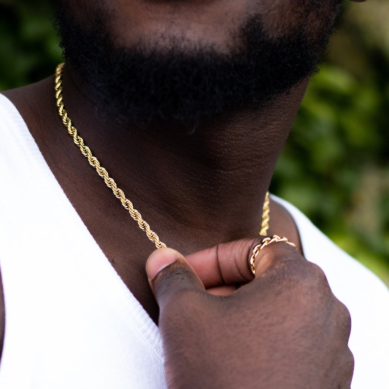 Puede incluir: Un collar de cadena de cuerda dorada usado por una persona con barba.