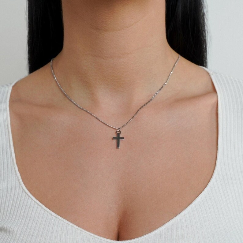 May include: A silver chain necklace with a small silver cross pendant.