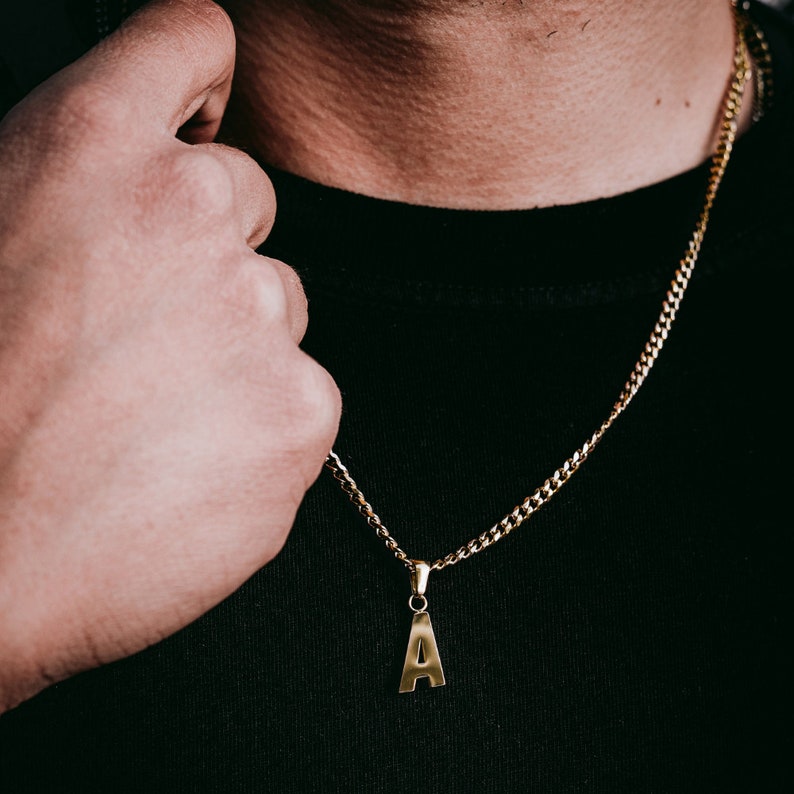 May include: A gold chain necklace with a pendant in the shape of the letter "A".