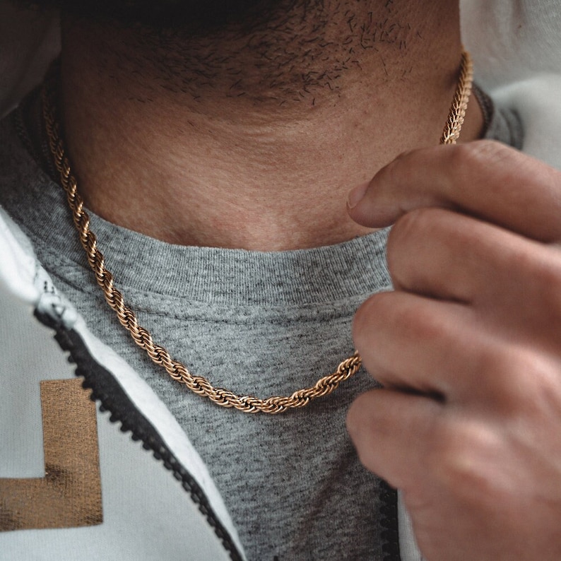 Puede incluir: Un collar de cadena de cuerda dorada que se lleva alrededor del cuello de una persona.