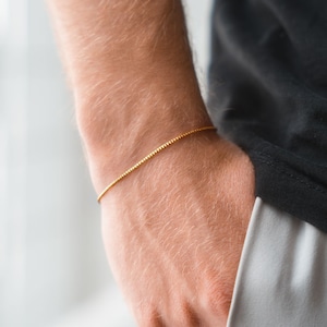 Puede incluir: Un brazalete de cadena fina de oro en la muñeca de una persona.