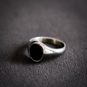 May include: A silver signet ring with a black oval stone.