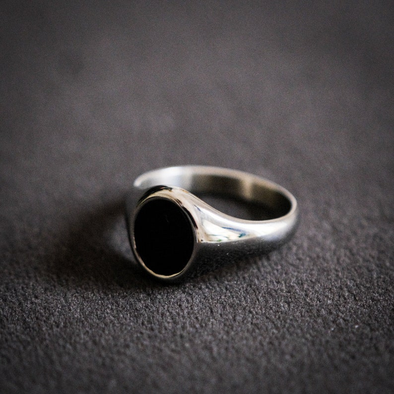 May include: A silver signet ring with a black oval stone.