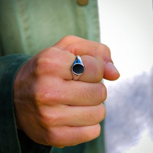 May include: A silver signet ring with a black oval stone.